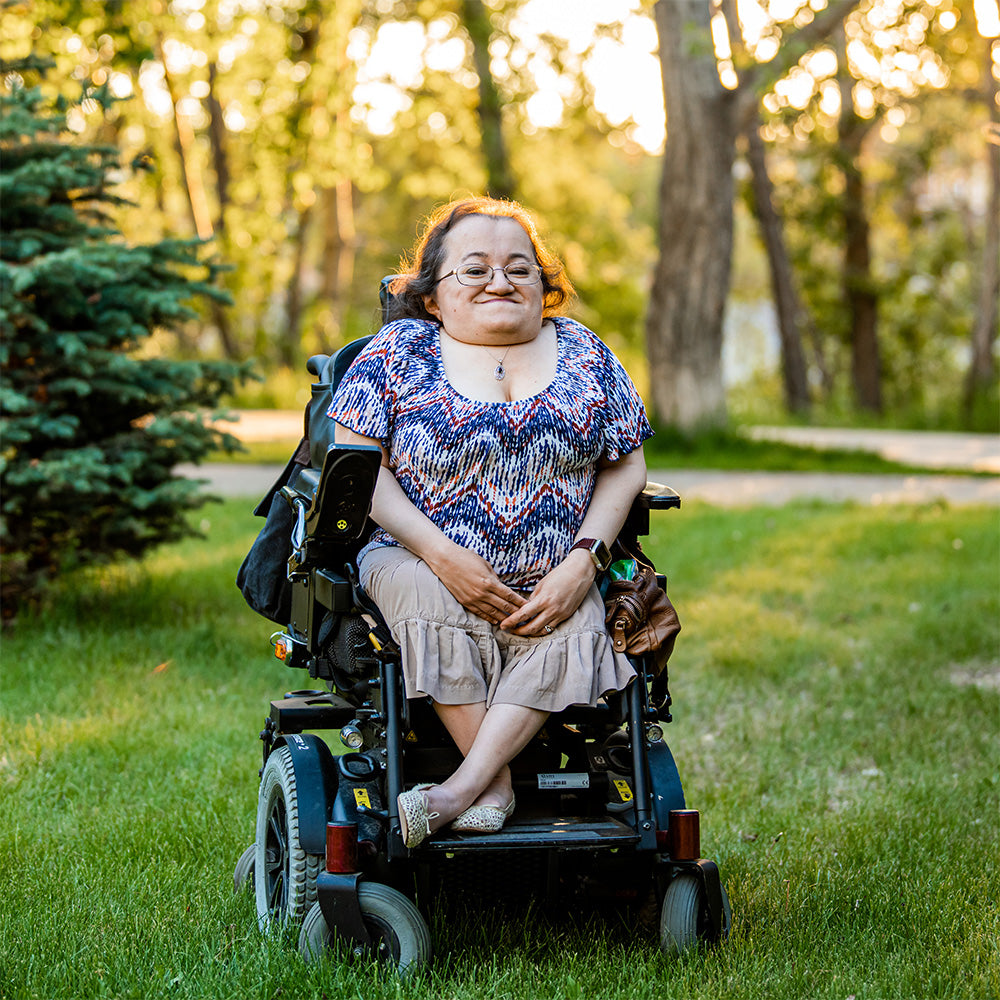Photo of Athena Cooper, digital and acrylic painter, seated outdoors in her power wheelchair